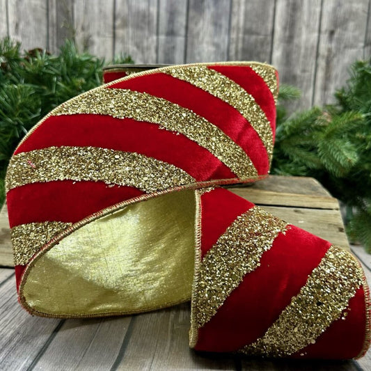 Red and gold striped decorative ribbon on a wooden surface with greenery in the background