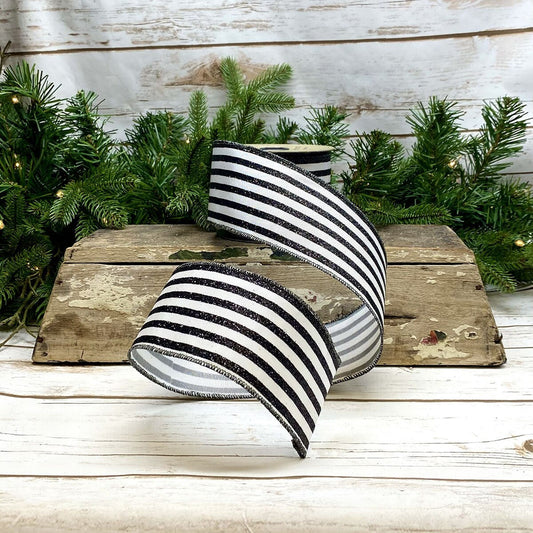Black and white striped ribbon on a wooden surface with greenery in the background