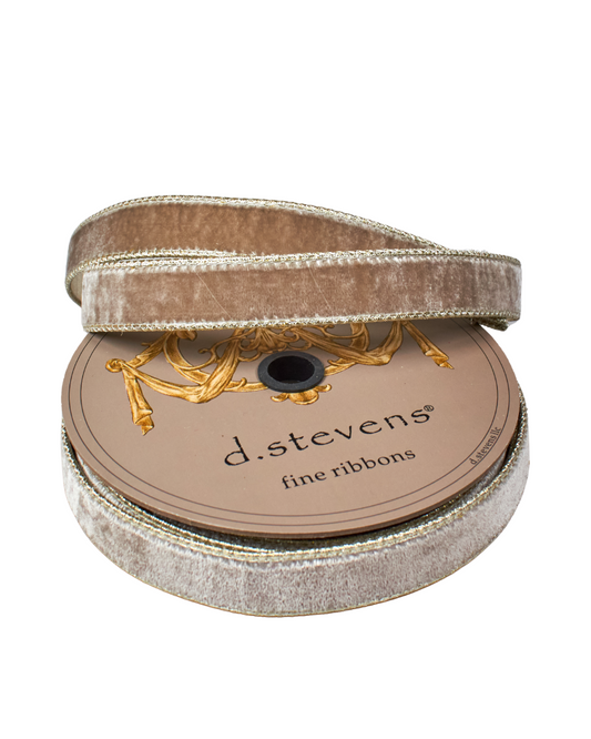 Spool of platinum ribbon with gold decorative element on a white background, branded 'd. stevens'.