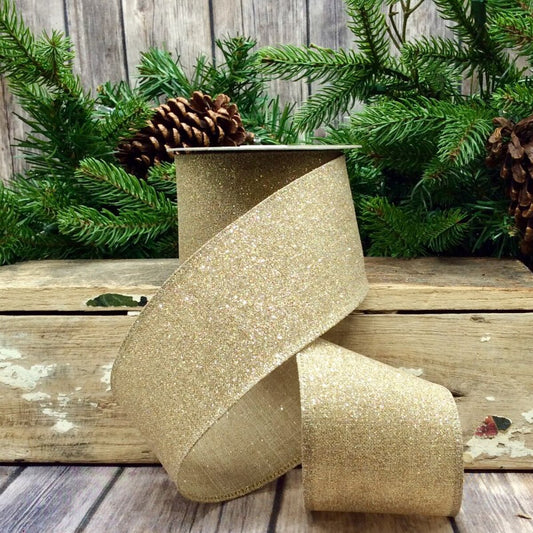 Gold glitter ribbon on a wooden surface with greenery in the background