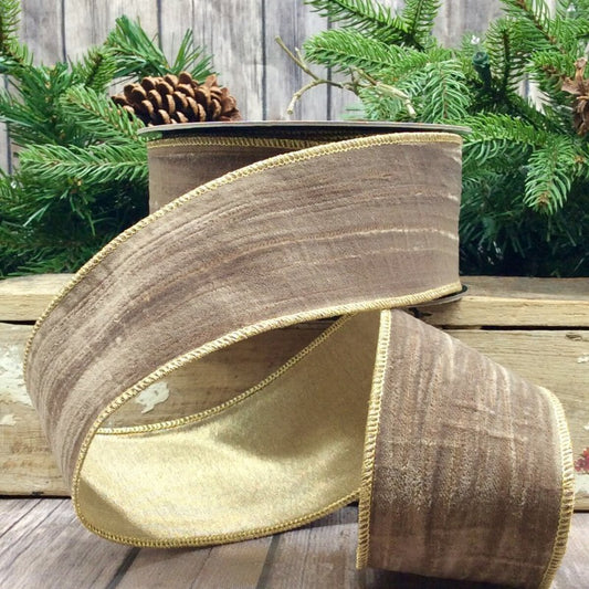 Brown and gold ribbon on a wooden surface with greenery in the background
