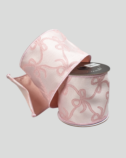 Spool of pink ribbon with bow pattern on a light gray background