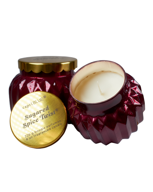 Red candle jar with gold lid labeled 'Capri Blue Sugared Spice Twist' on a white background