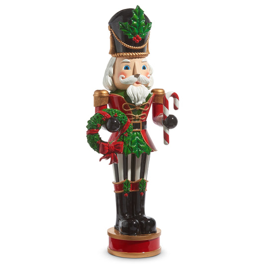 Decorative Christmas nutcracker figurine with a wreath and candy cane on a white background