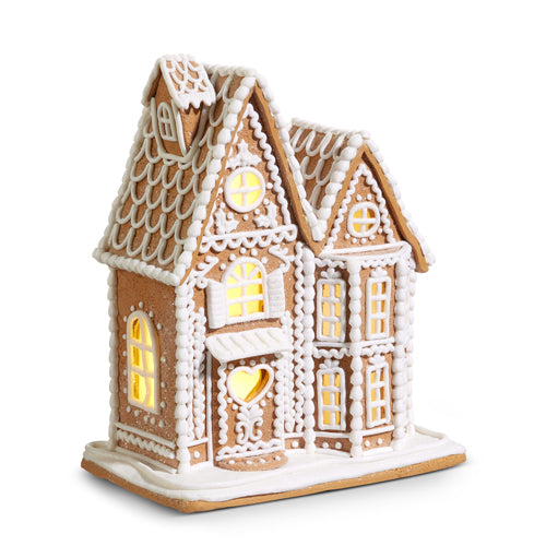 Clay dough decorative gingerbread house with lit windows on a white background