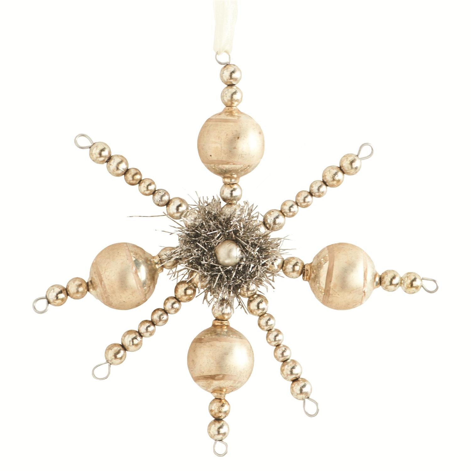 A vintage snowflake-shaped ornament in champagne color, adorned with small beads and a faux fur detail in the center.