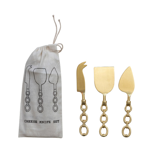 Set of gold cheese knives with a drawstring bag on a white background