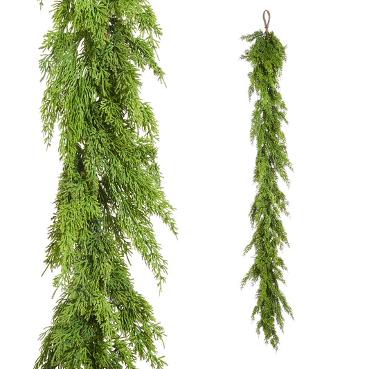 Two artificial green garlands hanging against a white background