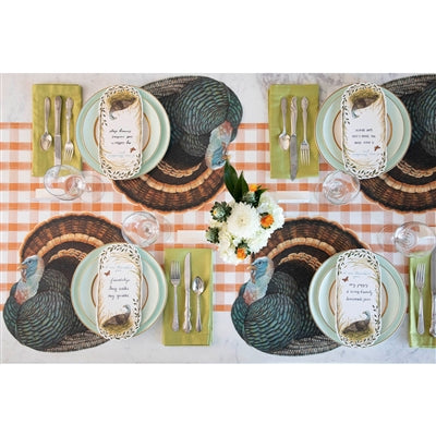 Thanksgiving table setting with turkey-themed place mats and checkered tablecloth.