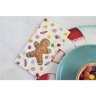 Colorful napkin with gingerbread man design next to a bowl of candy on a light gray surface.