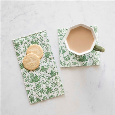 Two green patterned paper napkins with a mug and cookies on a marble surface