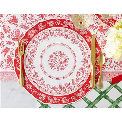 Red and white patterned placemat with gold cutlery on a matching tablecloth.