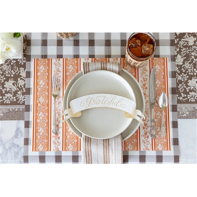Dinner setting with a checkered tablecloth, plate, cutlery, and glass.