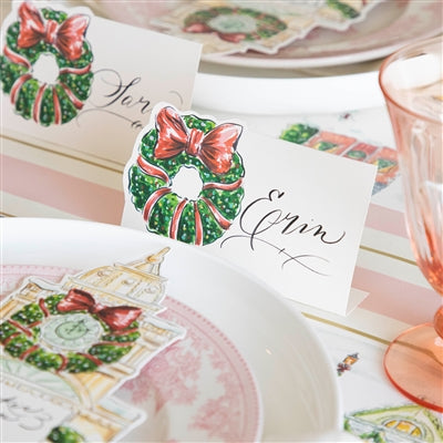 Decorative place cards with Christmas wreath designs on a table setting.