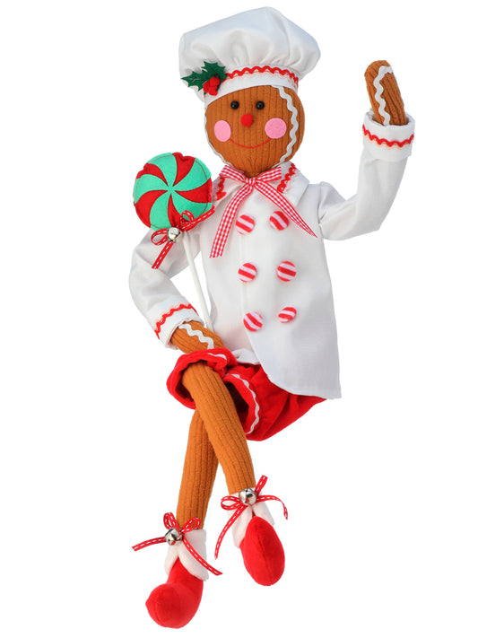 A felt gingerbread chef doll with a lollipop, dressed in a white outfit with red and green accents.