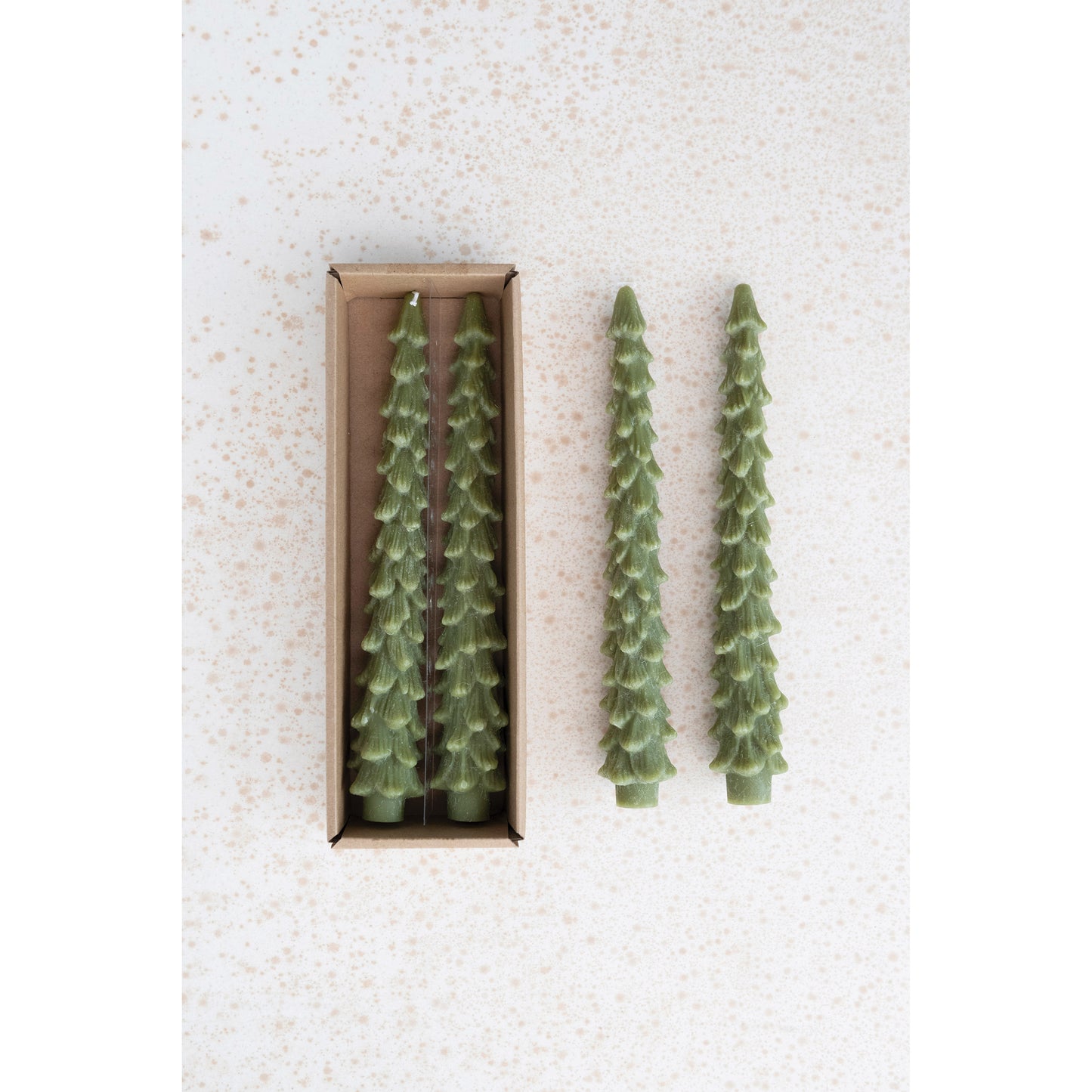 Two green candle trees next to a box containing more candle trees on a textured white background