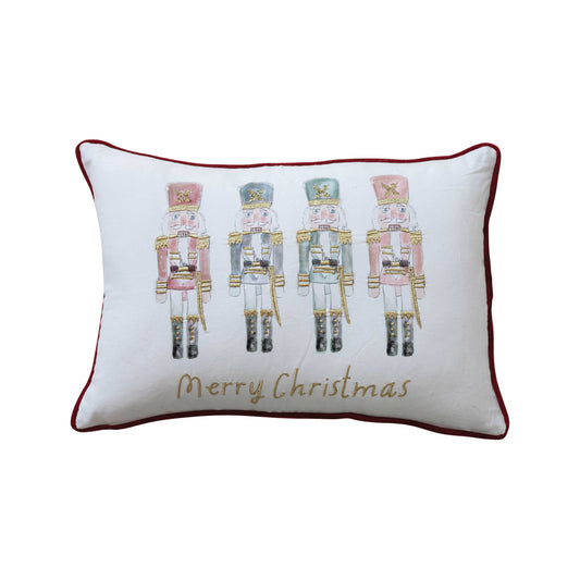 A rectangular lumbar pillow with a white background featuring a group of nutcrackers in pink uniforms, playing musical instruments, and the text 'Merry Christmas' with a red border.