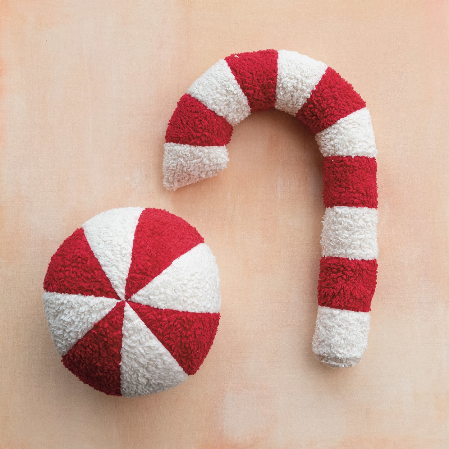 Red and white striped candy cane-shaped pillow on a beige background
