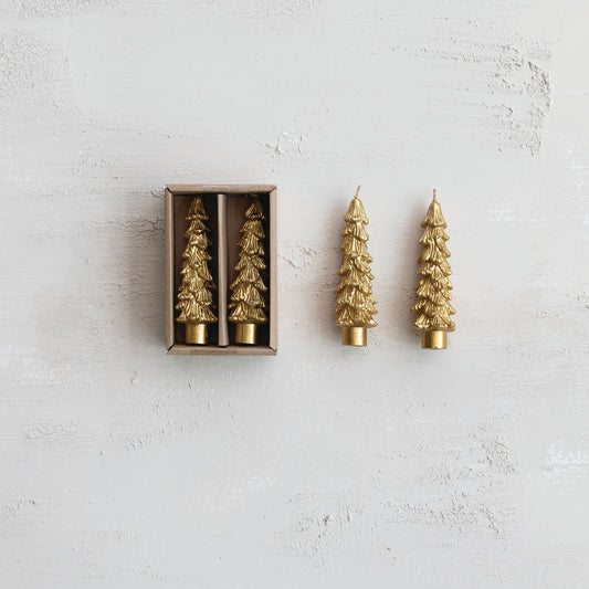 Gold Christmas tree-shaped candles with one out of the box on a light gray background