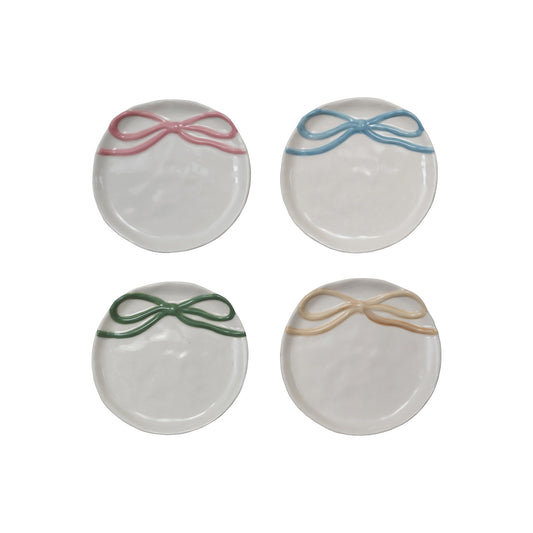 Four round ceramic coasters with colorful bow designs on a white background
