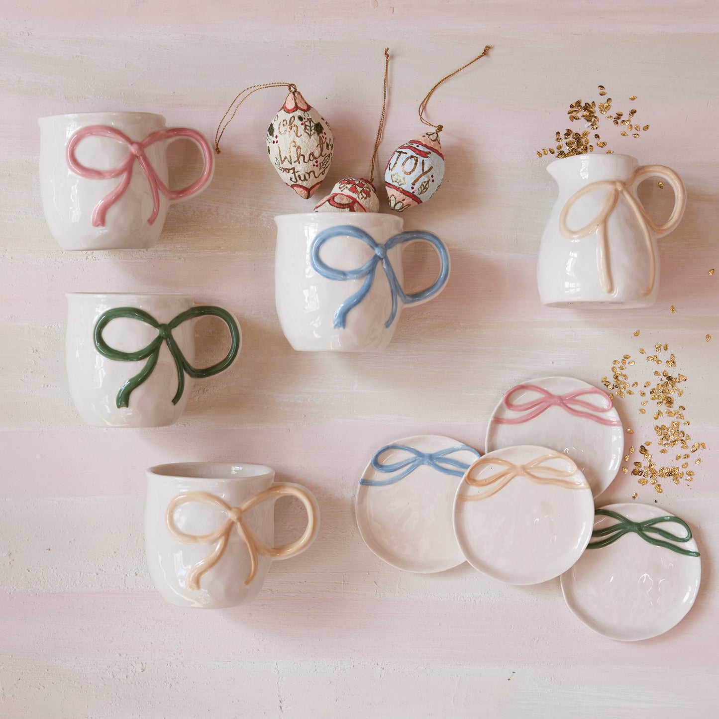 Set of ceramic mugs and plates with decorative bows on a light background