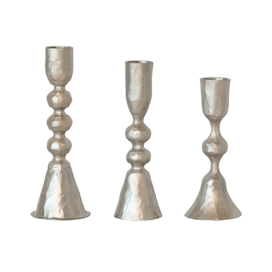 Three metallic candle holders of varying heights on a white background