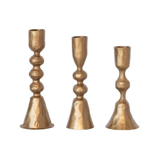 Three gold candle holders of varying heights on a white background