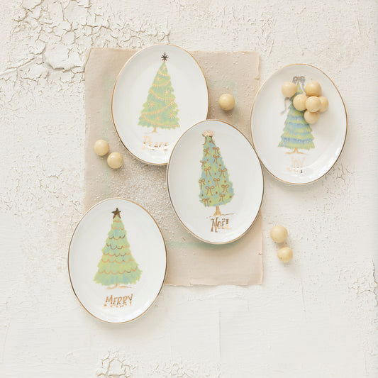 Four decorative plates with Christmas tree designs on a textured surface.