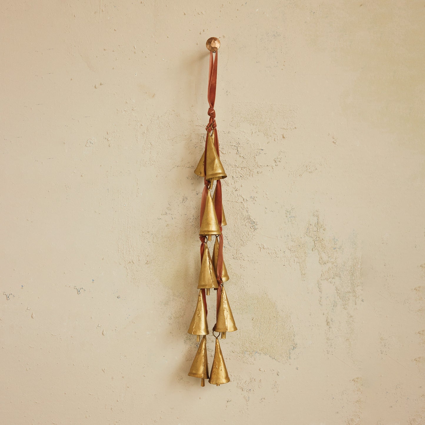 Brass bell wind chime on a beige wall