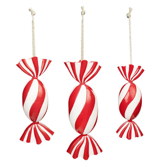 Three red and white striped candy ornaments hanging against a white background