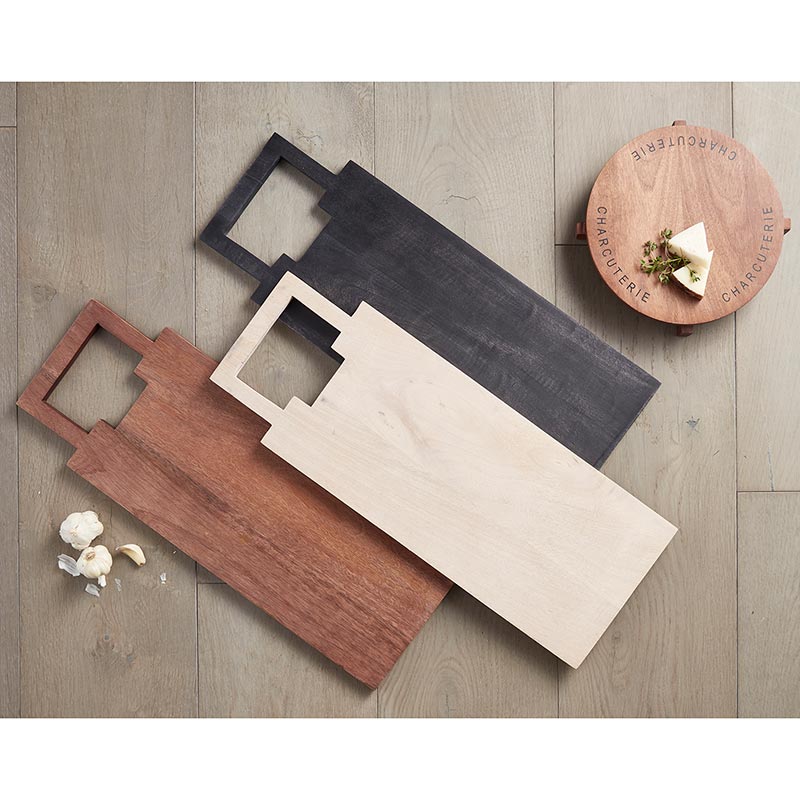 Set of wooden cutting boards in different colors on a wooden surface.