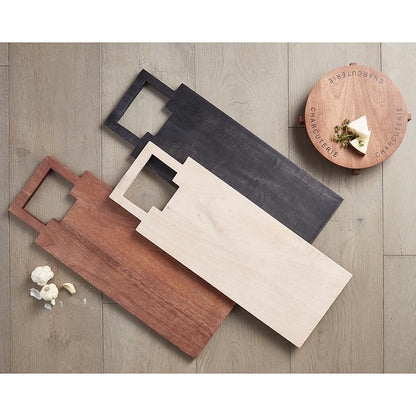 Set of wooden cutting boards in different colors on a wooden surface.