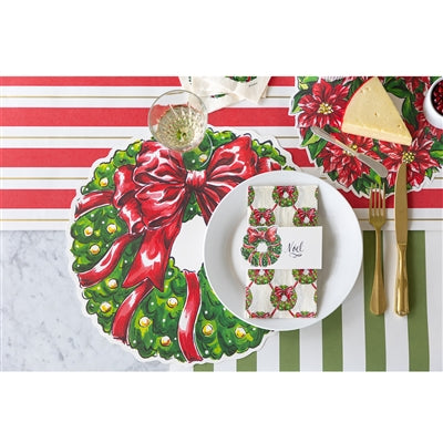 Christmas-themed table setting with a wreath placemat, striped tablecloth, and decorative items.