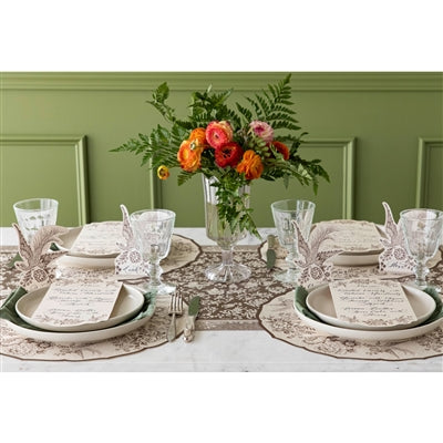 Elegant table setting with floral centerpiece against a green paneled wall.