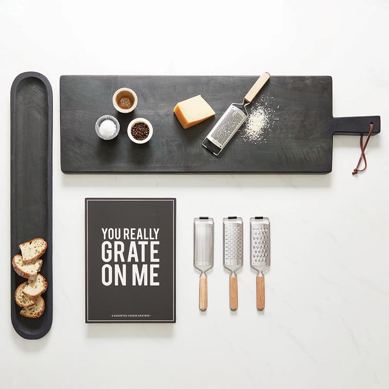 Set of cheese graters with a humorous sign and food items on a white background