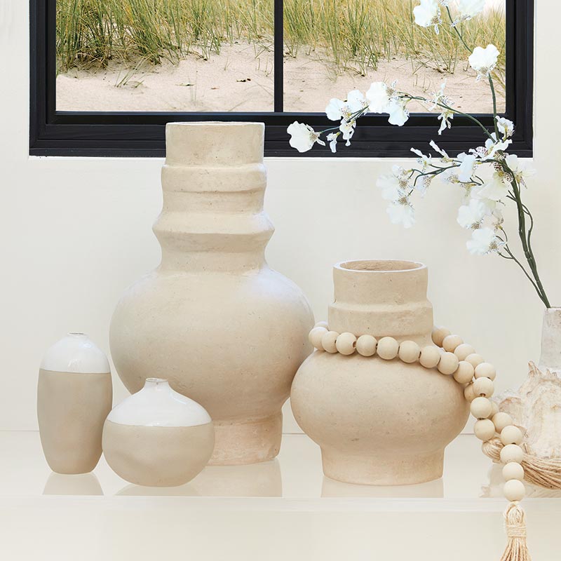Set of beige ceramic vases with a beach scene in the background
