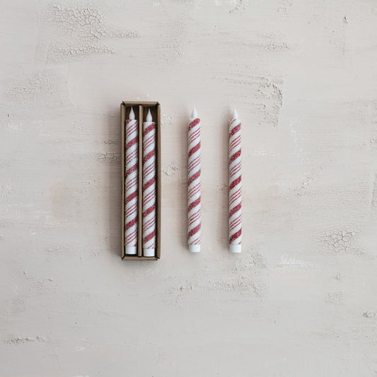 Set of striped LED candles with two candles outside its box on a light gray surface