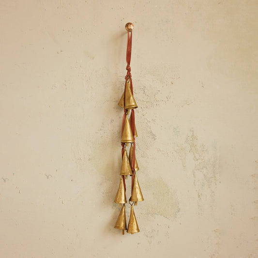 Brass bell wind chime on a beige wall